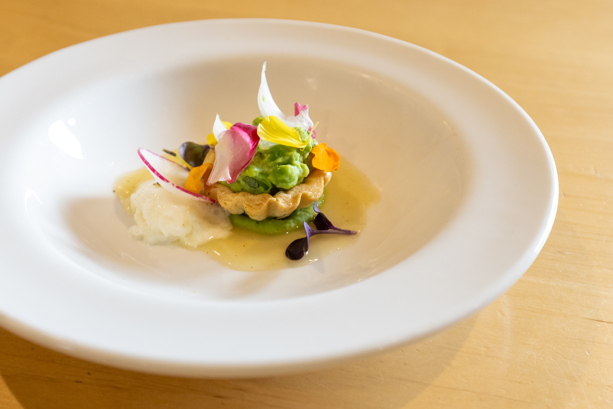 tartlet with colourful garnish on a white plate and wood table