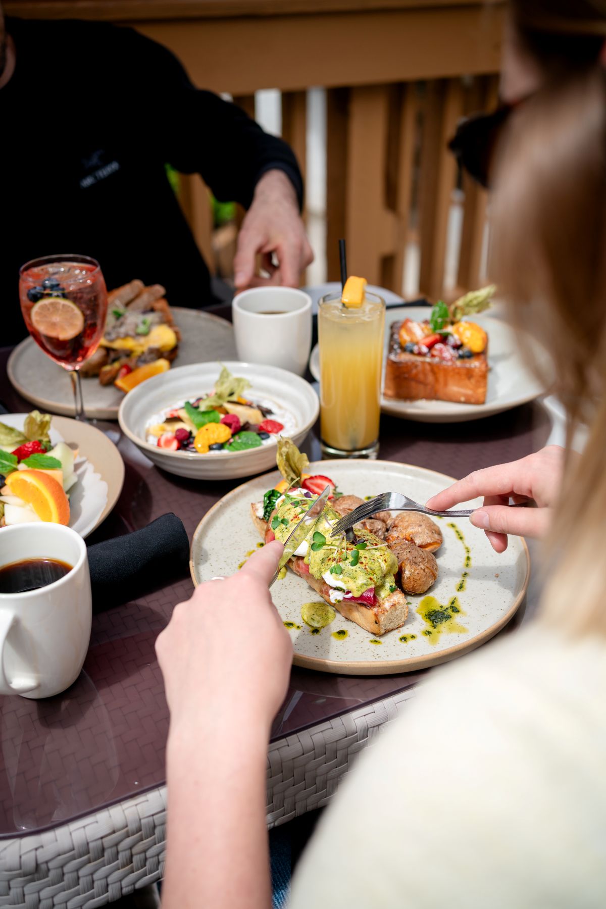 Outdoor patio dining at Alpha Bistro, Banff Rocky Mountain Resort, with guests enjoying breakfast and coffee.